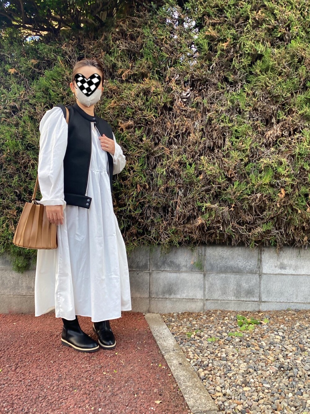 ホワイト系のワンピース、ブラック系のベストを着用したレディースの秋コーディネートの2枚目の写真