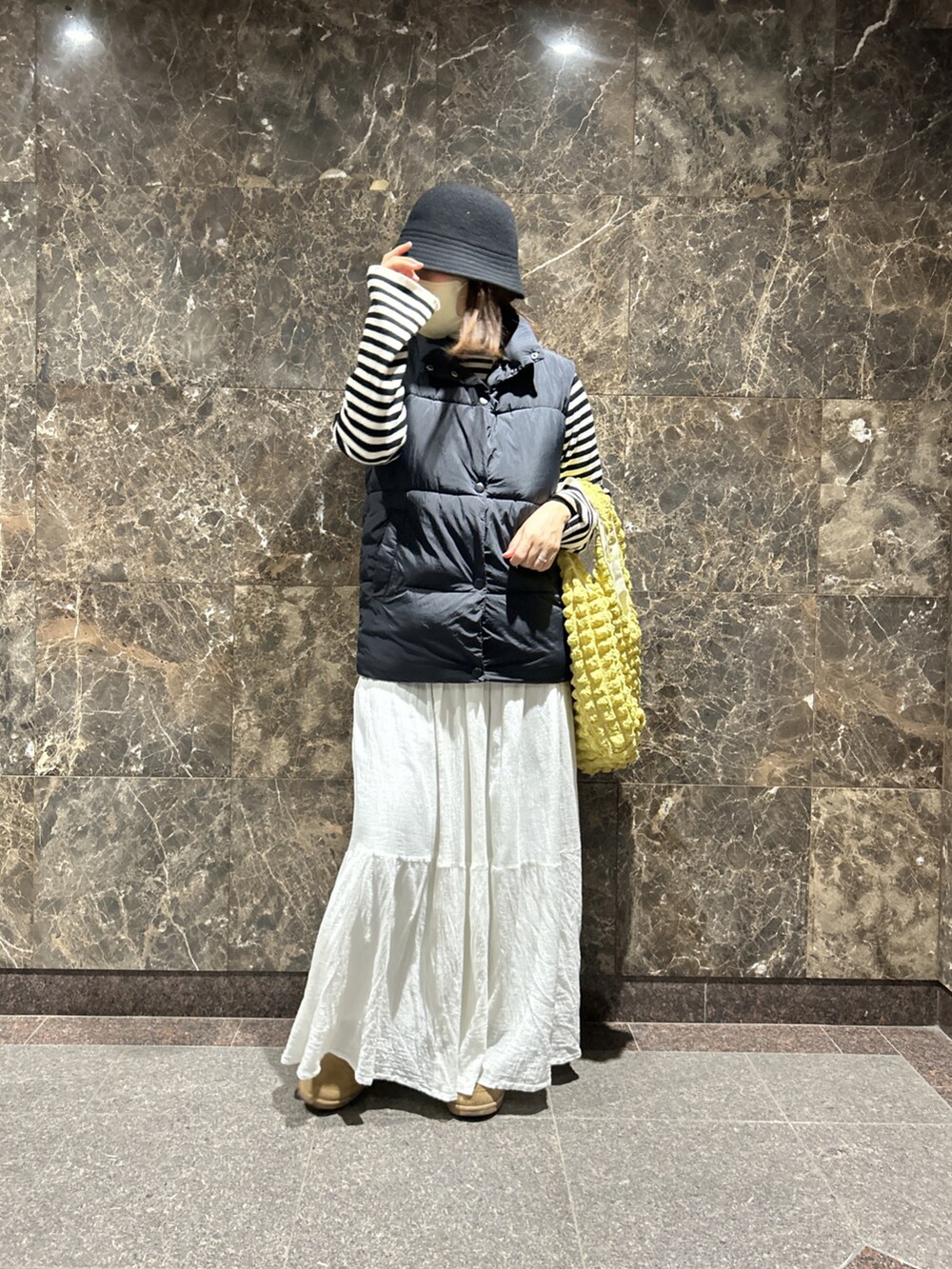 ブラック系のベスト、ホワイト系のスカート、ブラック系のトップスを着用したレディースの冬コーディネートの2枚目の写真