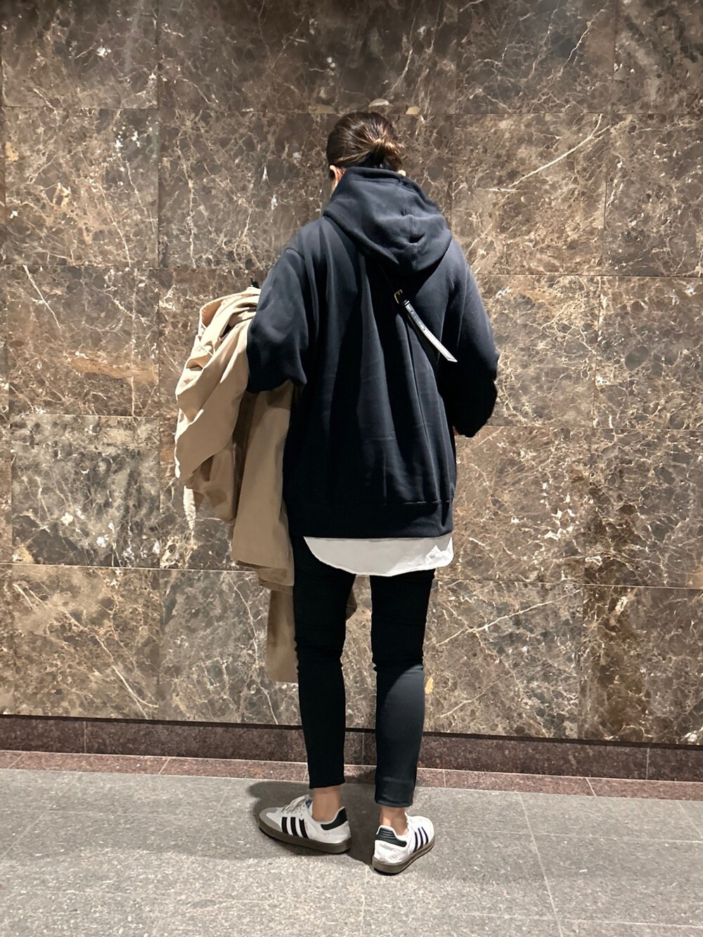 ブラック系のパーカー、ベージュ系のトレンチコート、ホワイト系のスニーカーを着用したレディースの冬コーディネートの4枚目の写真