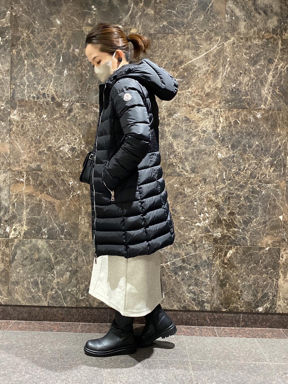 ブラック系のショルダーバッグ、ホワイト系のジャンパースカート、ブラック系のニット/セーターを着用したレディースの冬コーディネートの4枚目の写真