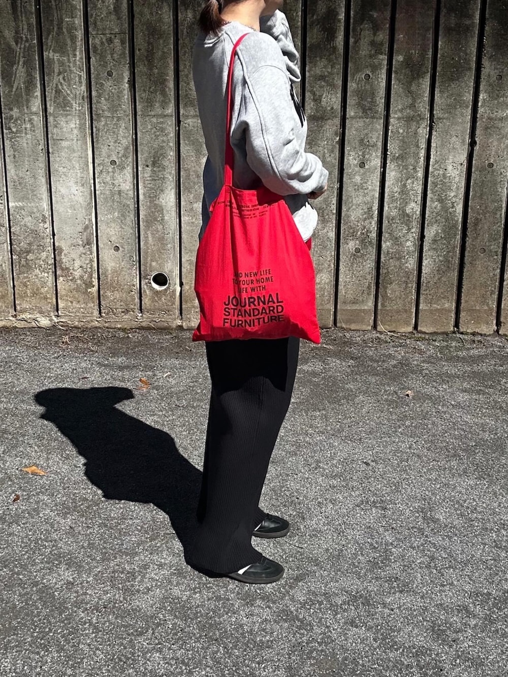 グレー系のスウェット、ブラック系のスカート、レッド系のトートバッグを着用したレディースの春コーディネートの2枚目の写真