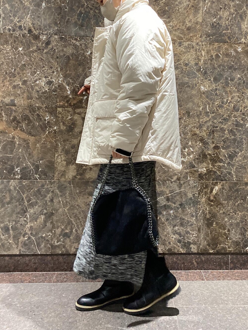 グレー系のダウンジャケット/コート、ブラック系のスカート、ブラック系のハンドバッグを着用したレディースの冬コーディネートの2枚目の写真