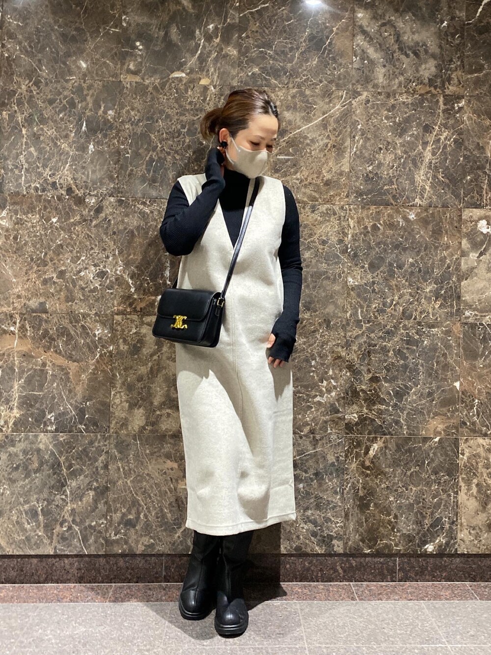 ブラック系のショルダーバッグ、ホワイト系のジャンパースカート、ブラック系のニット/セーターを着用したレディースの冬コーディネートの2枚目の写真