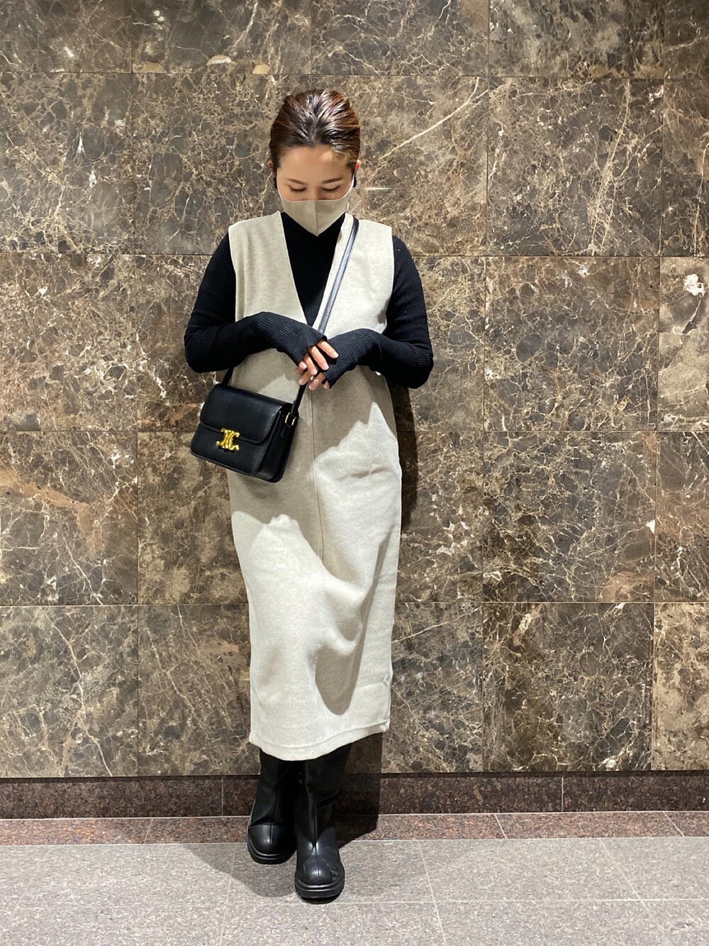 ブラック系のショルダーバッグ、ホワイト系のジャンパースカート、ブラック系のニット/セーターを着用したレディースの冬コーディネートの3枚目の写真