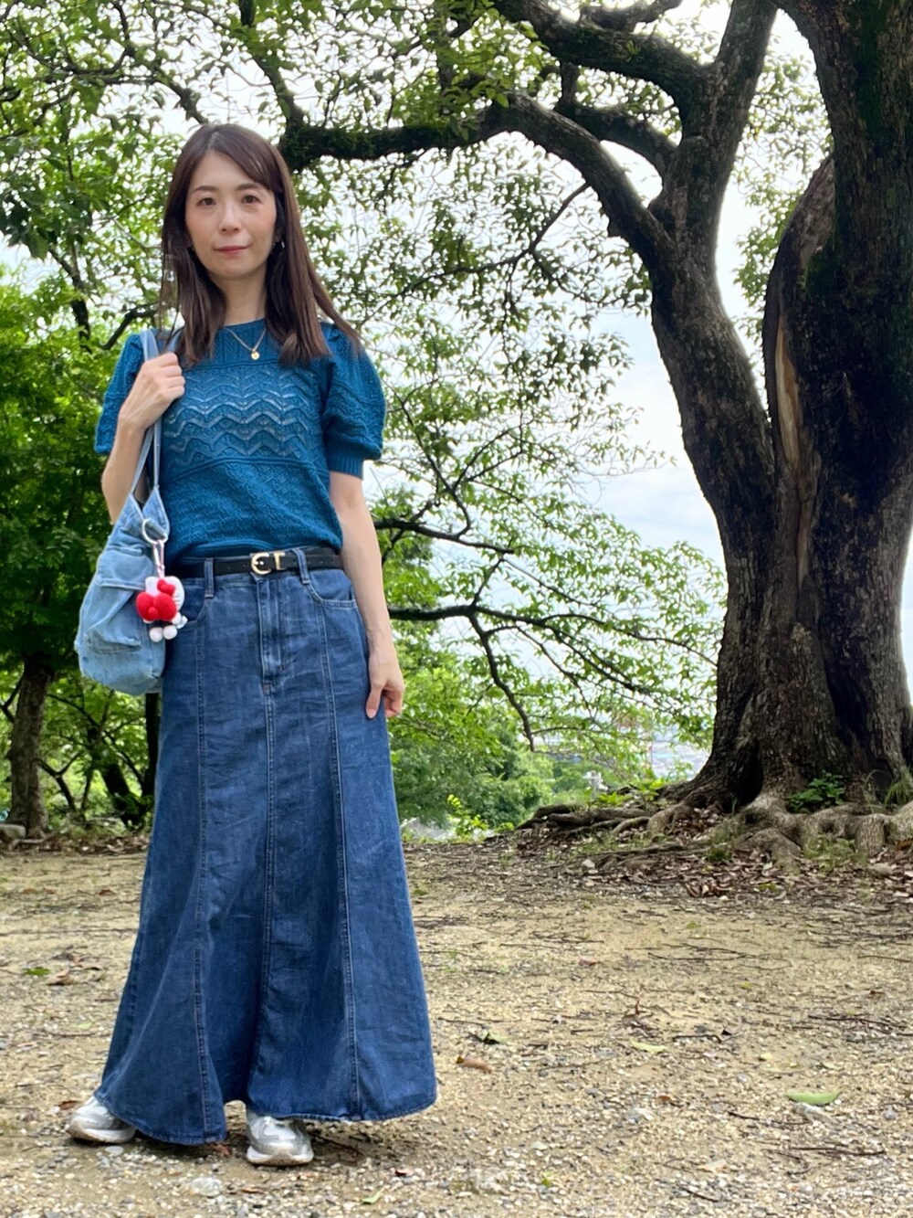 その他のデニムスカート、ホワイト系のスニーカー、ブルー系のニット/セーターを着用したレディースの夏コーディネートの3枚目の写真