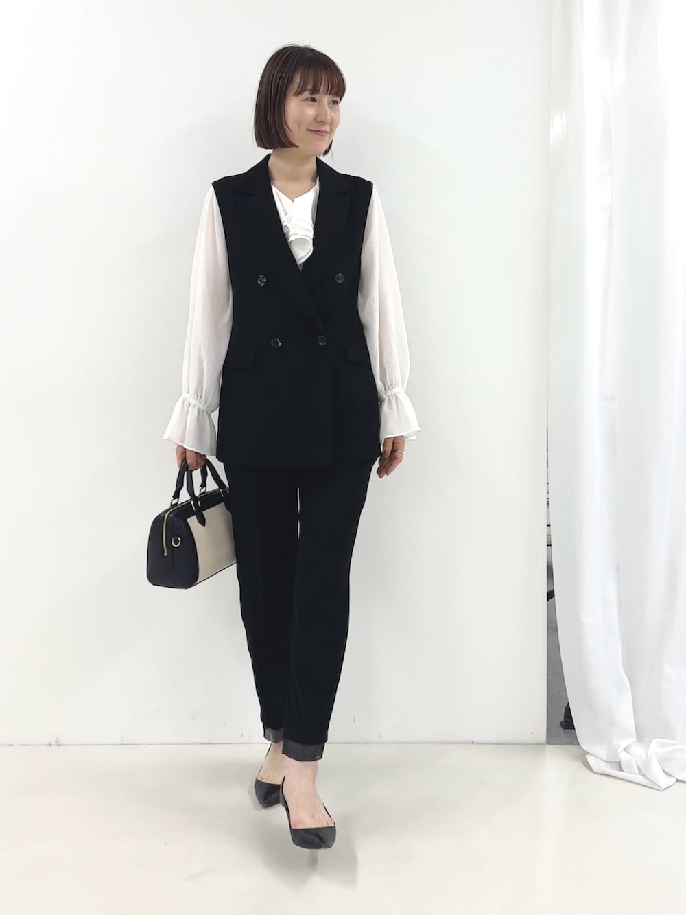 ブラック系のベスト、ホワイト系のシャツ/ブラウス、ブラック系のその他パンツを着用したレディースの冬コーディネートの3枚目の写真