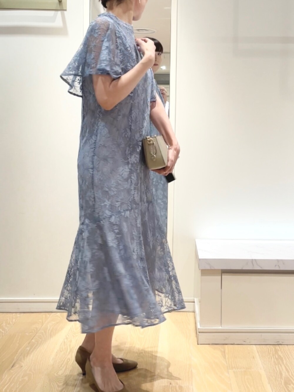 ベージュ系のショルダーバッグ、ブルー系のワンピース、ゴールド系のイヤリングを着用したレディースの秋コーディネートの6枚目の写真