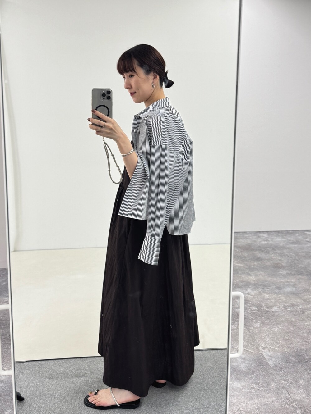 ブルー系のトートバッグ、シルバー系のサンダル、ブラウン系のワンピースを着用したレディースの夏コーディネートの2枚目の写真