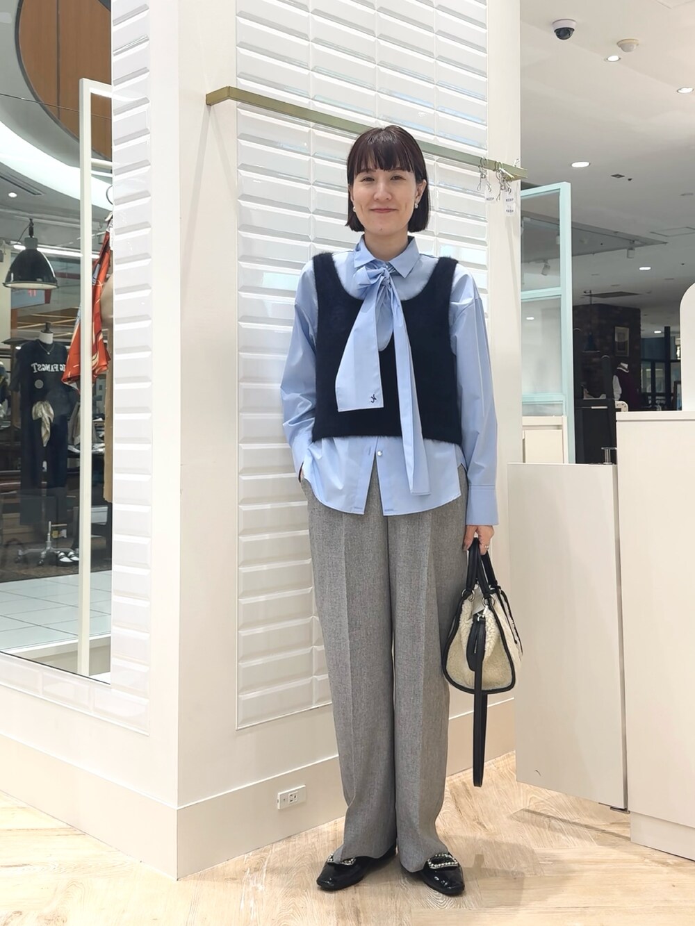 ホワイト系のボストンバッグ、ブルー系のベスト、ブルー系のシャツ/ブラウスを着用したレディースの秋コーディネートの8枚目の写真