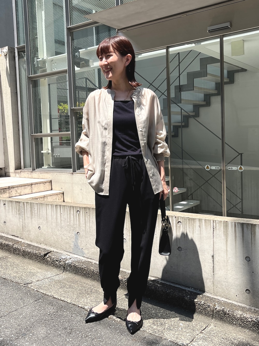 ブラック系のショルダーバッグ、ベージュ系のシャツ/ブラウス、ブラック系のその他パンツを着用したレディースの夏コーディネートの3枚目の写真