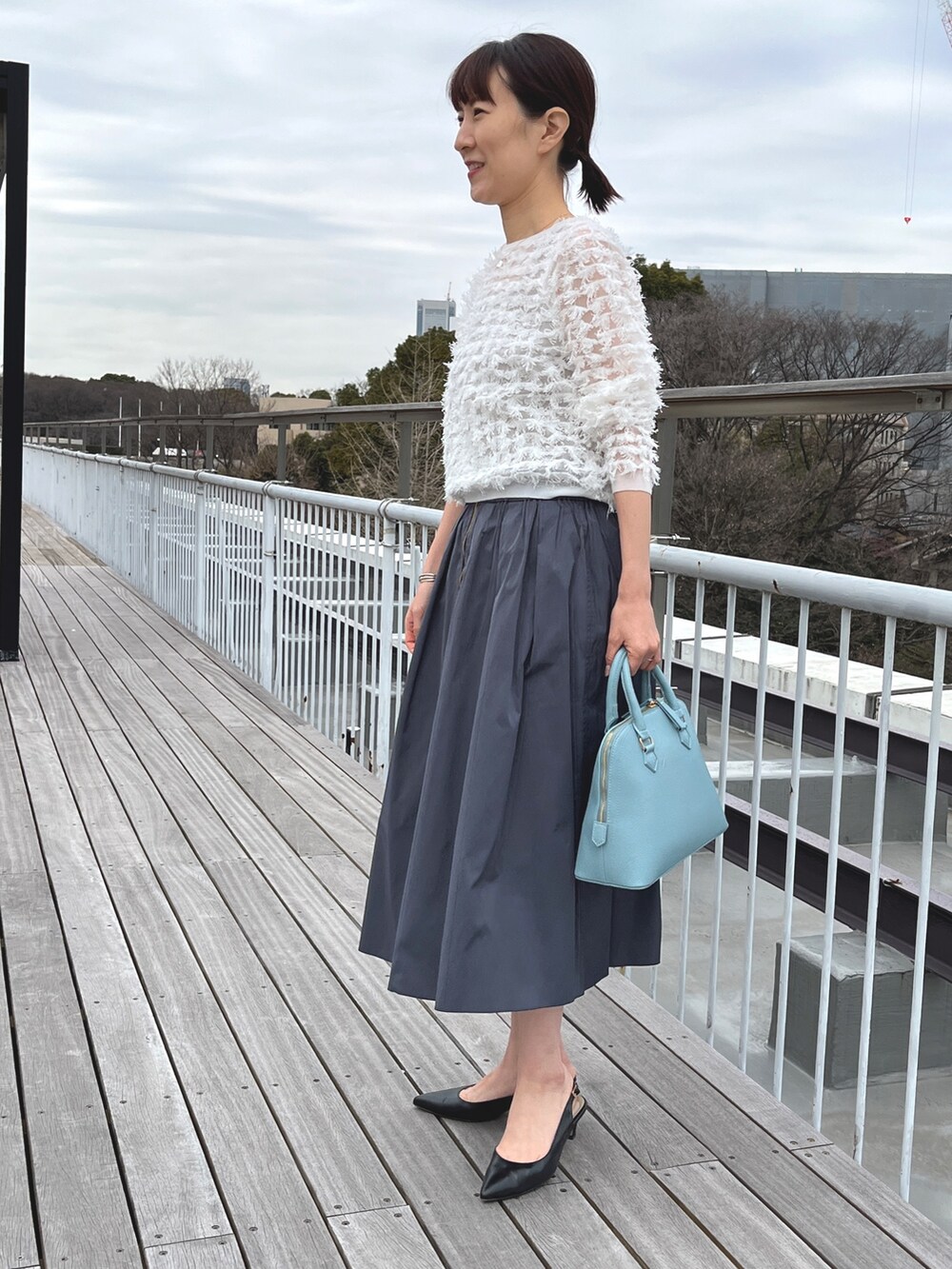 ブルー系のボストンバッグ、ブラック系のパンプス、グレー系のスカートを着用したレディースの冬コーディネートの3枚目の写真