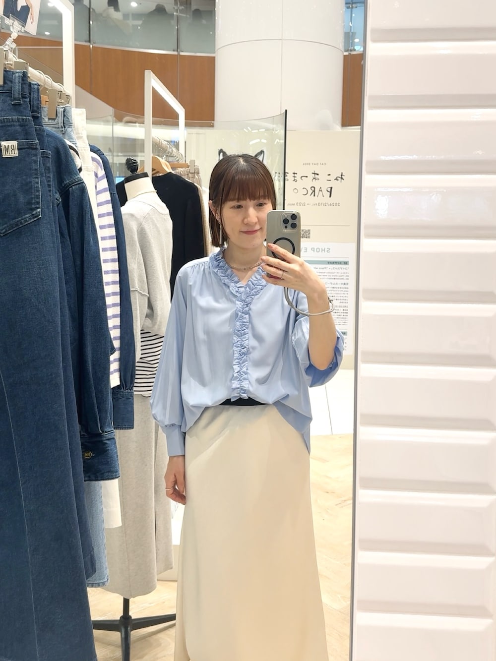 ブルー系のシャツ/ブラウス、ホワイト系のスカート、グレー系のネックレスを着用したレディースの春コーディネートの3枚目の写真