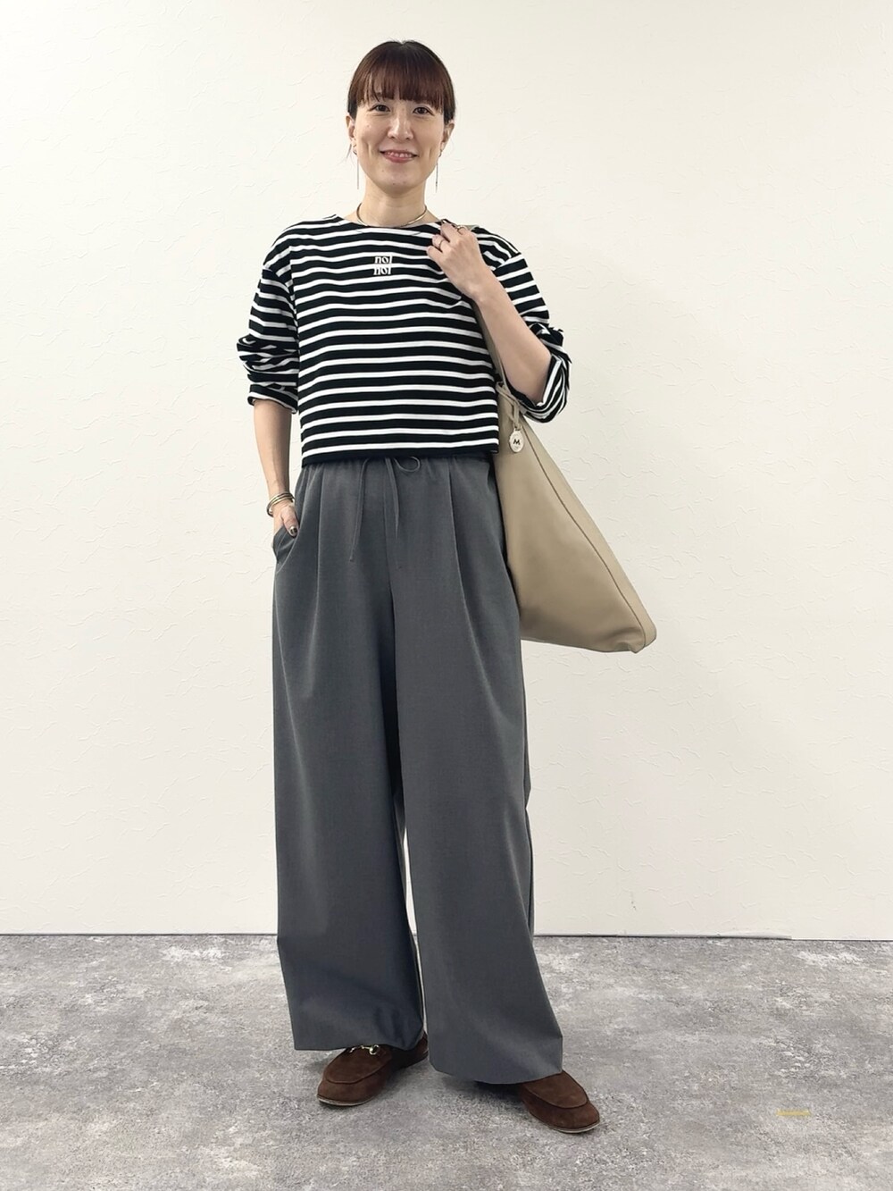 ブラック系のTシャツ/カットソー、ベージュ系のショルダーバッグ、グレー系のその他パンツを着用したレディースの秋コーディネートの8枚目の写真