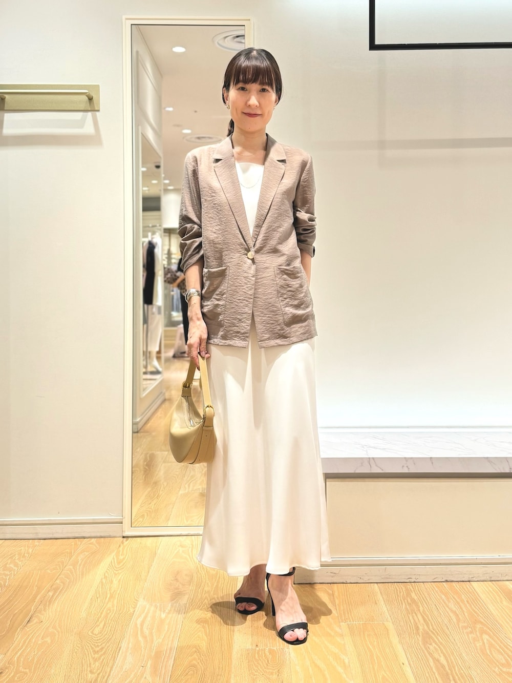 グリーン系のテーラードジャケット、ホワイト系のタンクトップ、ホワイト系のスカートを着用したレディースの夏コーディネートの5枚目の写真