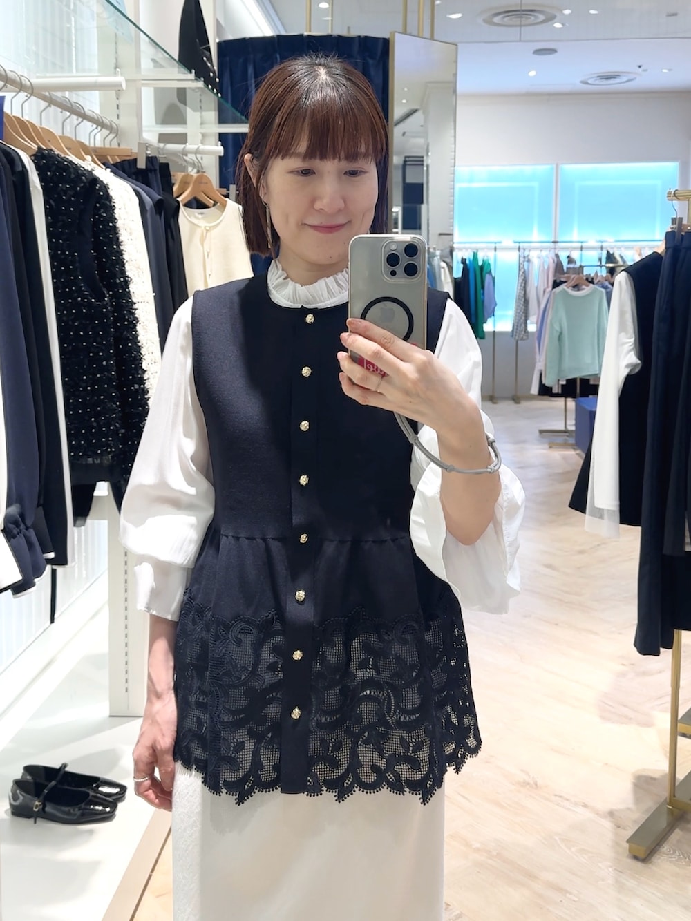 ホワイト系のスカート、ブルー系のベスト、ホワイト系のシャツ/ブラウスを着用したレディースの春コーディネートの3枚目の写真