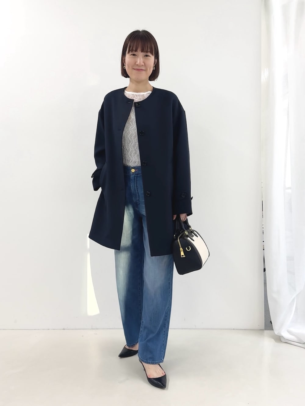 ブラック系のボストンバッグ、ホワイト系のTシャツ/カットソー、ブルー系のステンカラーコートを着用したレディースの冬コーディネートの3枚目の写真