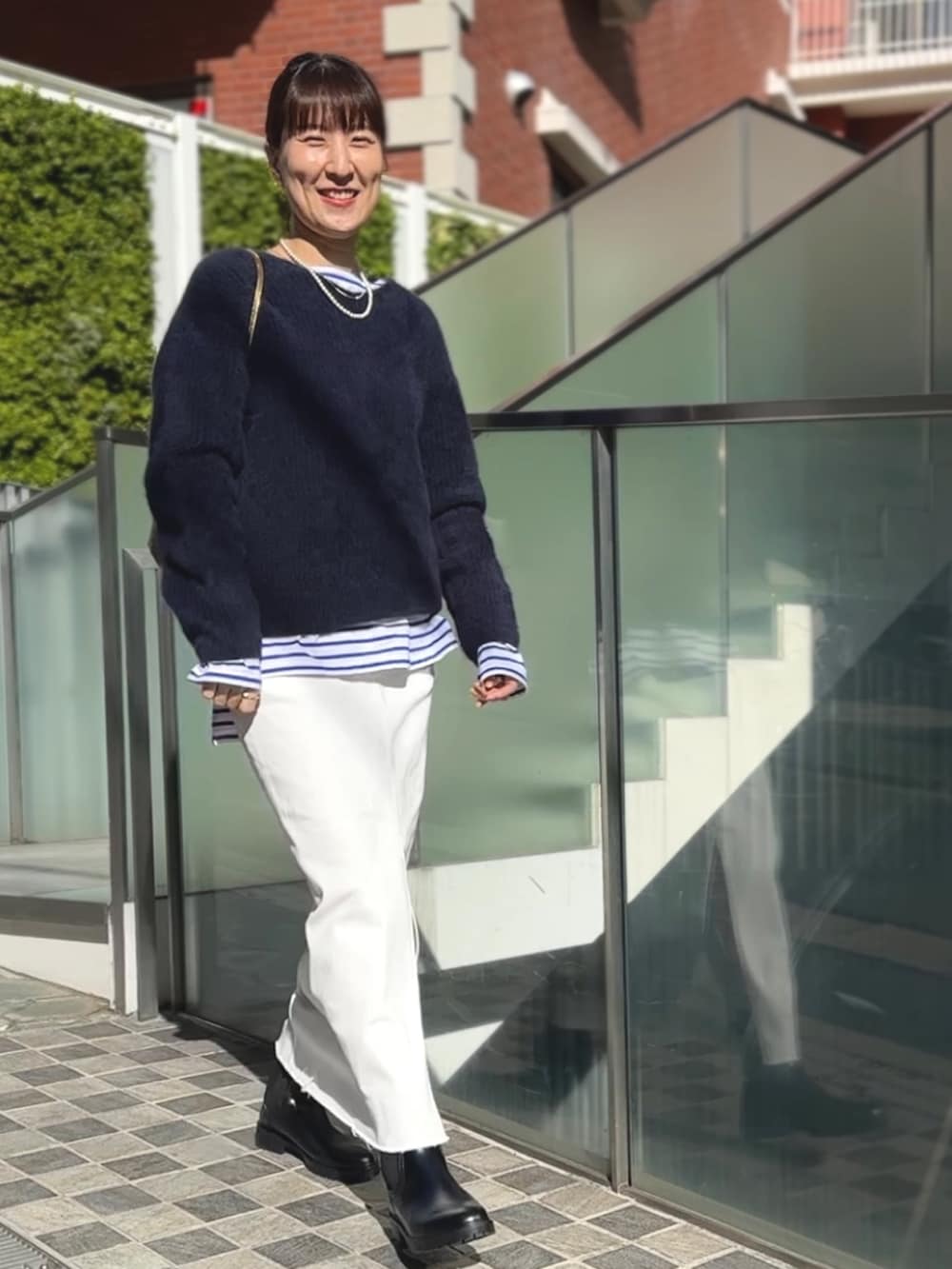 ゴールド系のクラッチバッグ、ブラック系のブーツ、ホワイト系のデニムスカートを着用したレディースの冬コーディネートの2枚目の写真