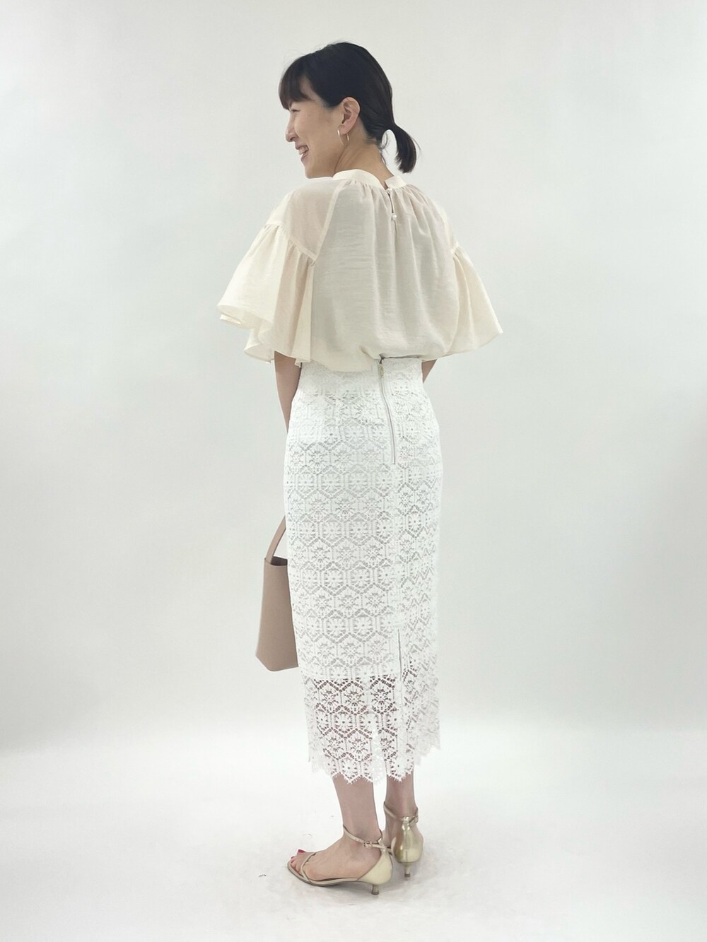 ゴールド系のサンダル、ピンク系のトートバッグ、ホワイト系のシャツ/ブラウスを着用したレディースの春コーディネートの3枚目の写真