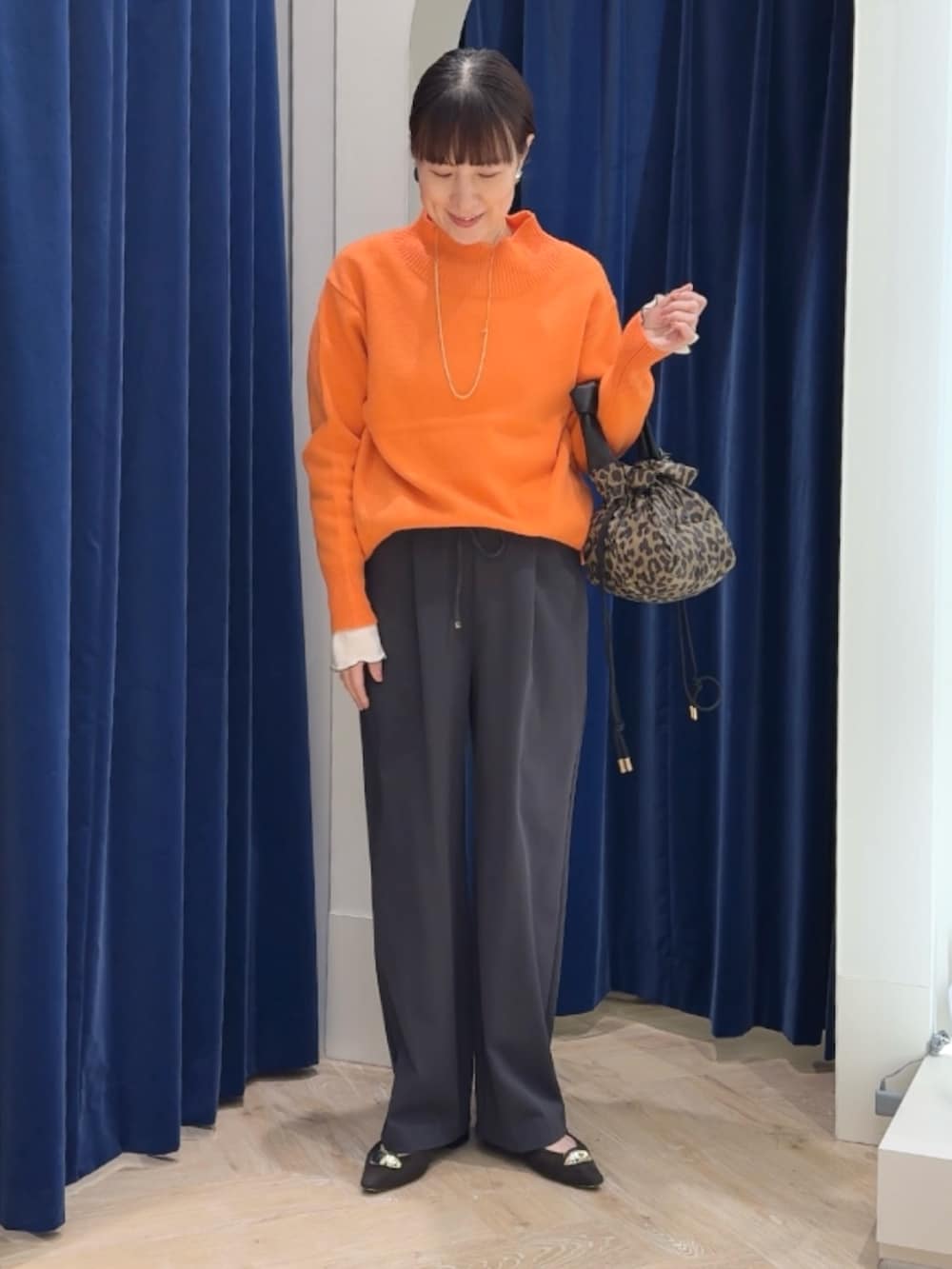 オレンジ系のニット/セーター、グレー系のその他パンツ、ホワイト系のTシャツ/カットソーを着用したレディースの冬コーディネートの3枚目の写真