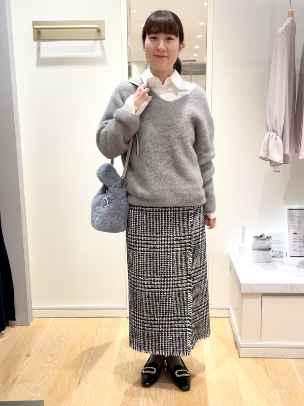 ブラック系のスカート、グレー系のニット/セーター、ブルー系のトートバッグを着用したレディースの冬コーディネートの8枚目の写真