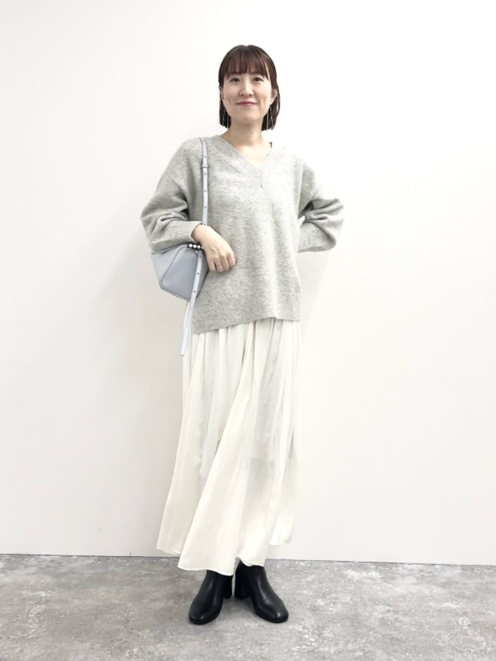 グレー系のニット/セーター、ブルー系のショルダーバッグ、ホワイト系のスカートを着用したレディースの冬コーディネートの10枚目の写真