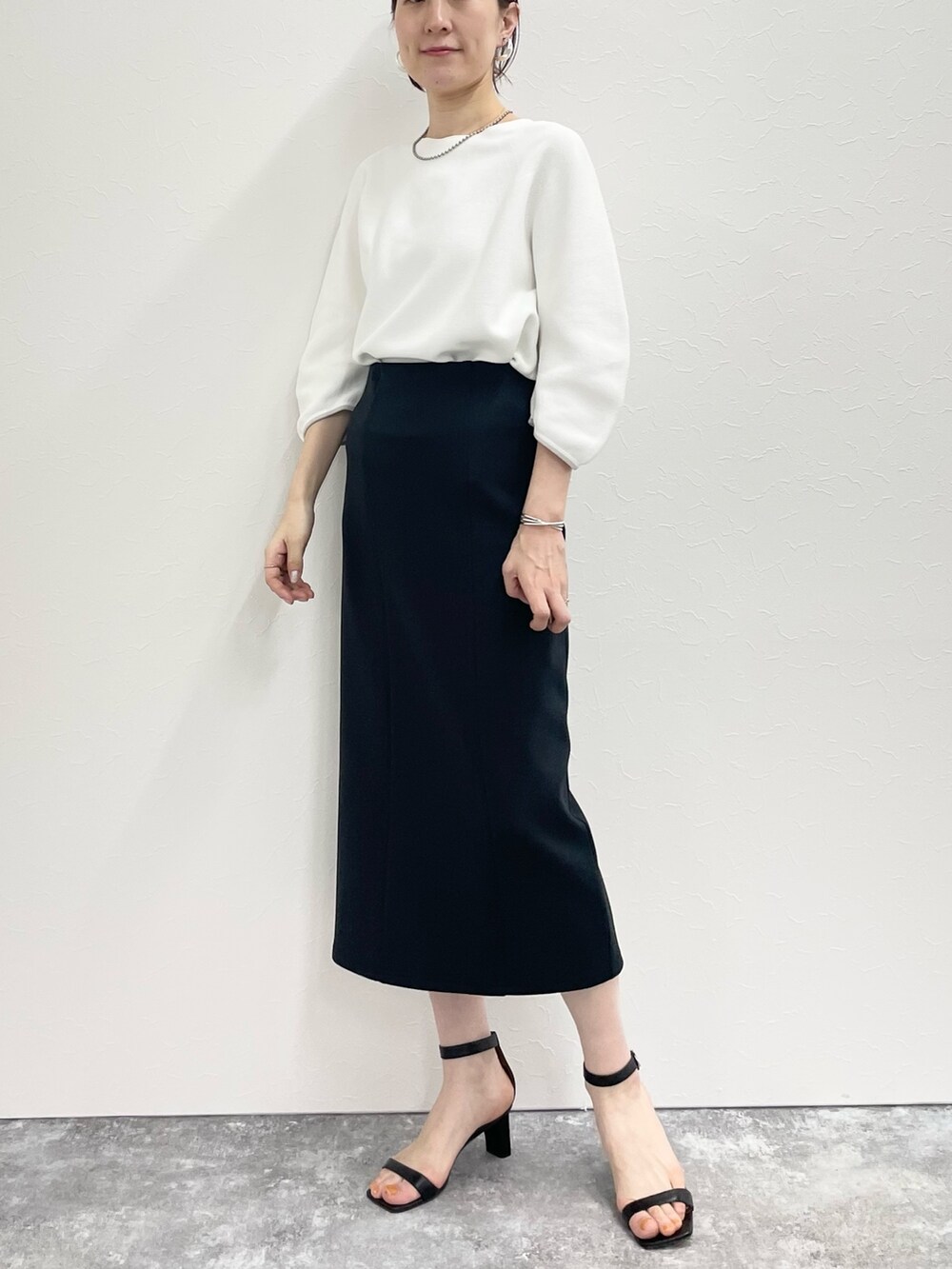 ブラック系のスカート、ホワイト系のニット/セーターを着用したレディースの春コーディネートの6枚目の写真