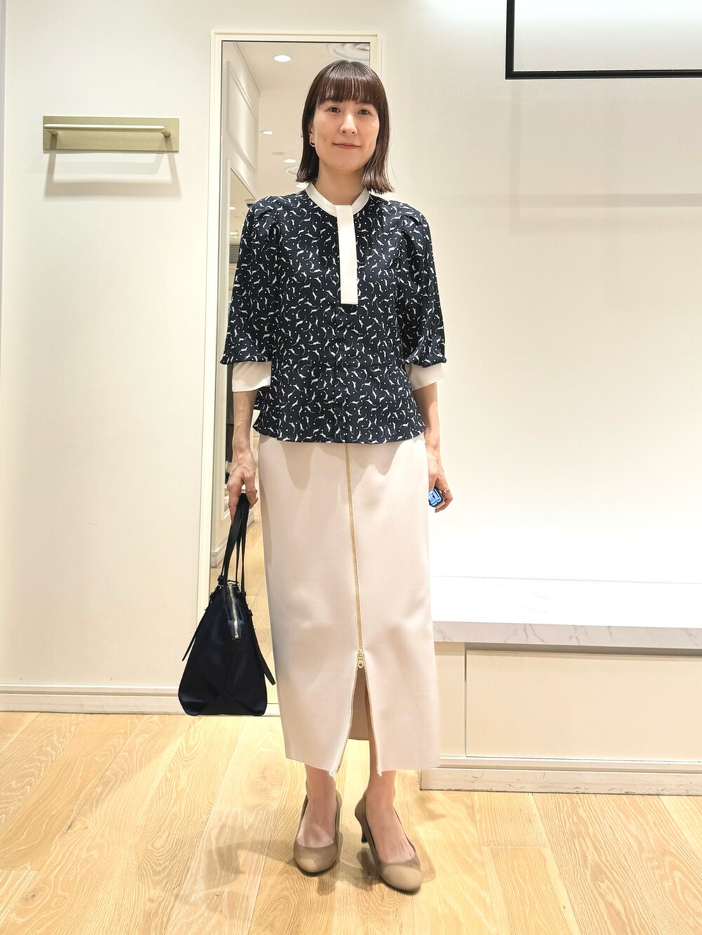 ベージュ系のスカート、ブルー系のトートバッグ、ブルー系のシャツ/ブラウスを着用したレディースの秋コーディネートの6枚目の写真