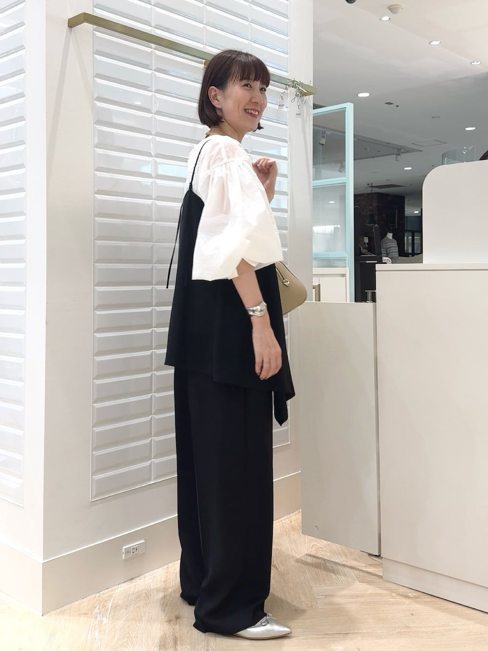 ブラック系のその他パンツ、ホワイト系のシャツ/ブラウス、ベージュ系のショルダーバッグを着用したレディースの秋コーディネートの4枚目の写真