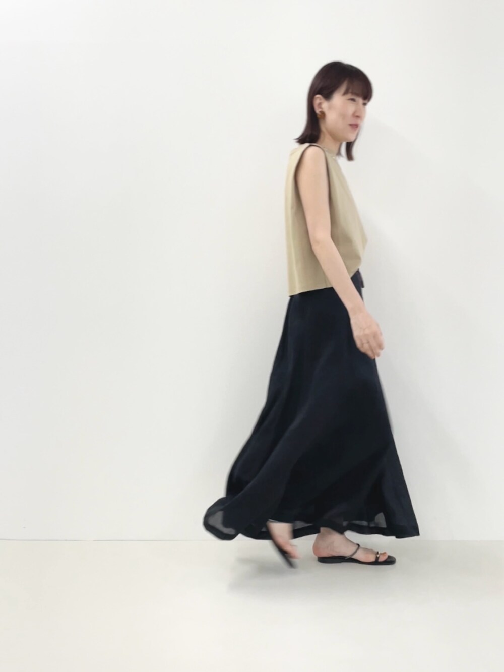 ブラック系のサンダル、ベージュ系のTシャツ/カットソー、ブラック系のスカートを着用したレディースの夏コーディネートの8枚目の写真
