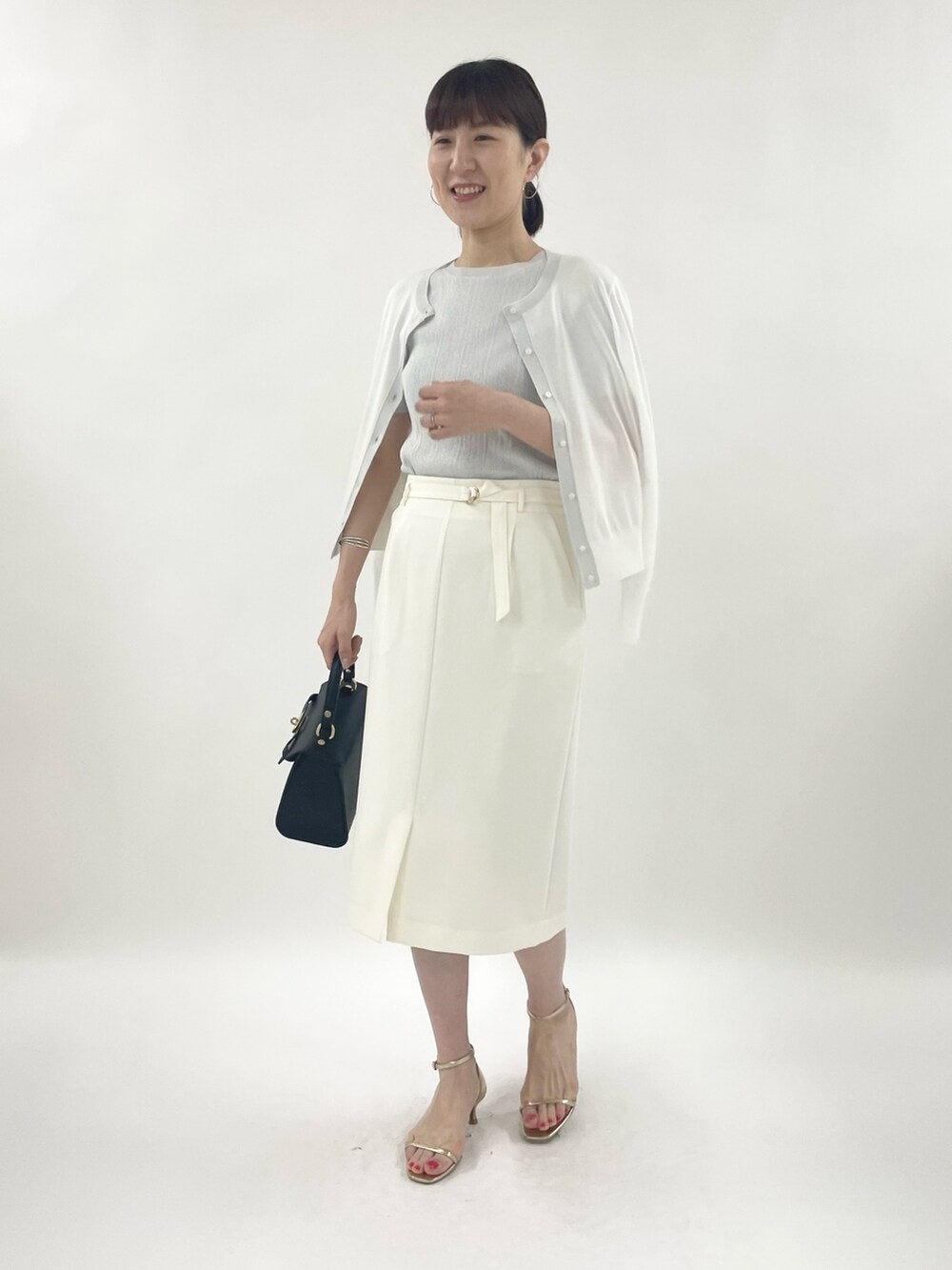 ゴールド系のサンダル、ブラック系のショルダーバッグ、シルバー系のニット/セーターを着用したレディースの春コーディネートの4枚目の写真