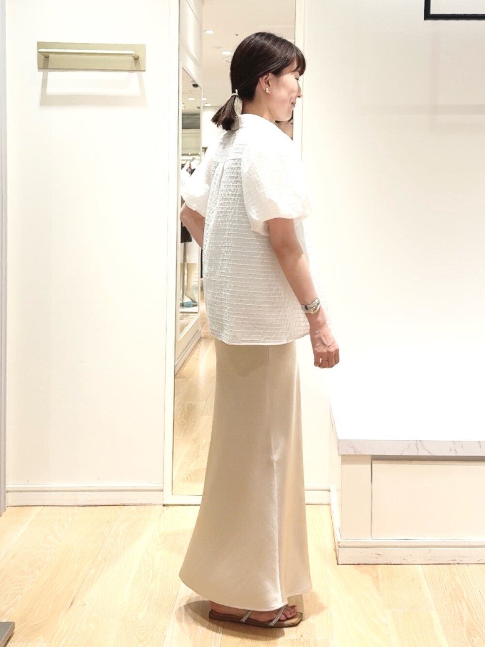 ベージュ系のスカート、ホワイト系のシャツ/ブラウス、ゴールド系のバレッタ/ヘアクリップを着用したレディースの夏コーディネートの5枚目の写真