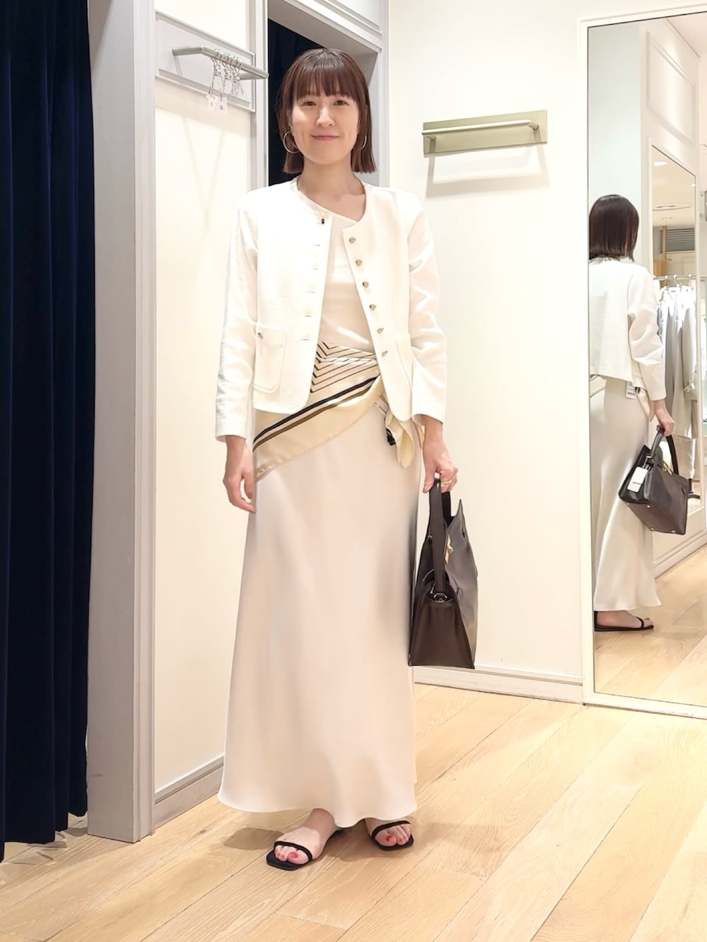 ホワイト系のタンクトップ、ホワイト系のノーカラージャケット、ホワイト系のスカートを着用したレディースの春コーディネートの7枚目の写真