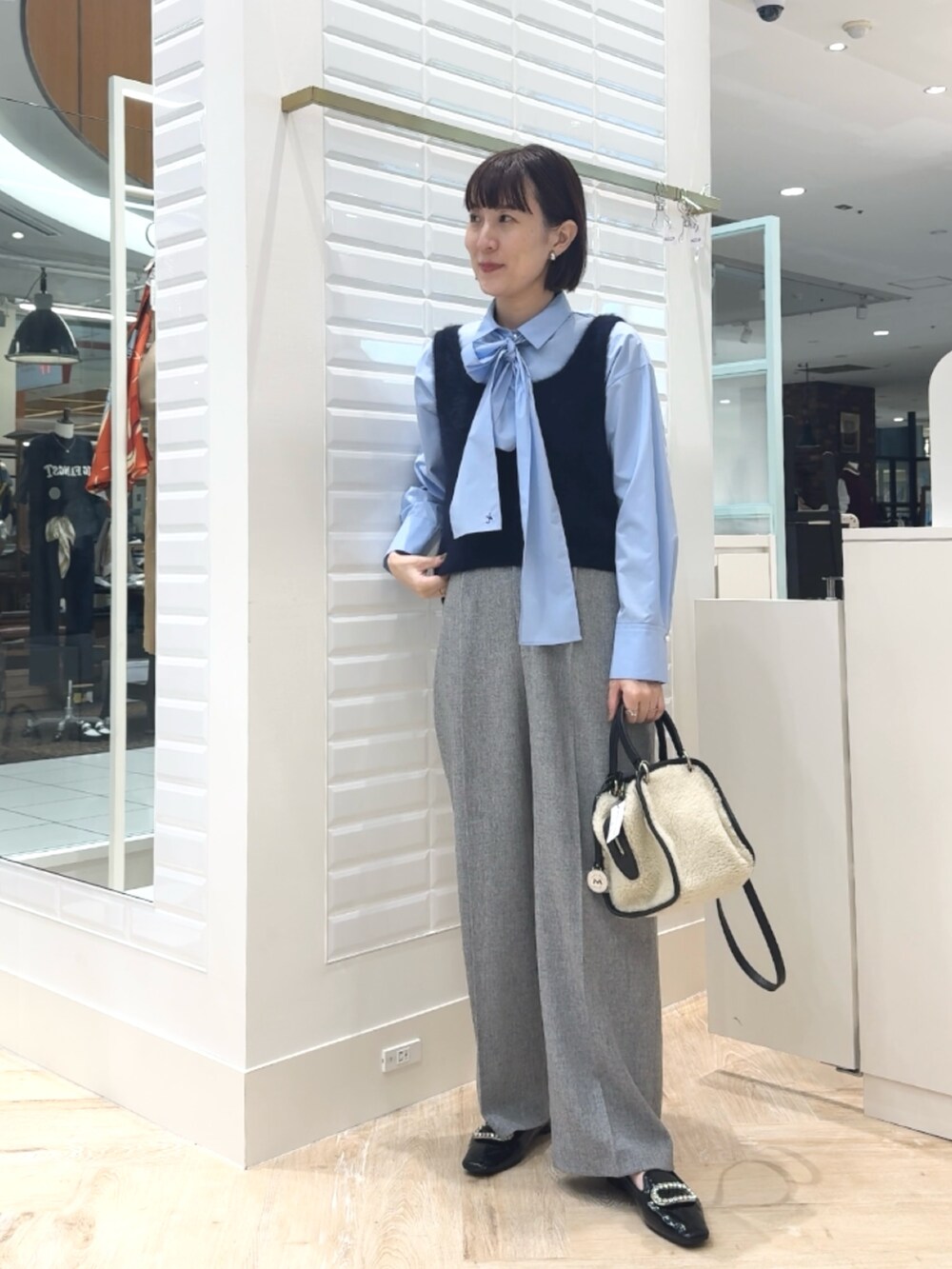 ホワイト系のボストンバッグ、ブルー系のベスト、ブルー系のシャツ/ブラウスを着用したレディースの秋コーディネートの2枚目の写真