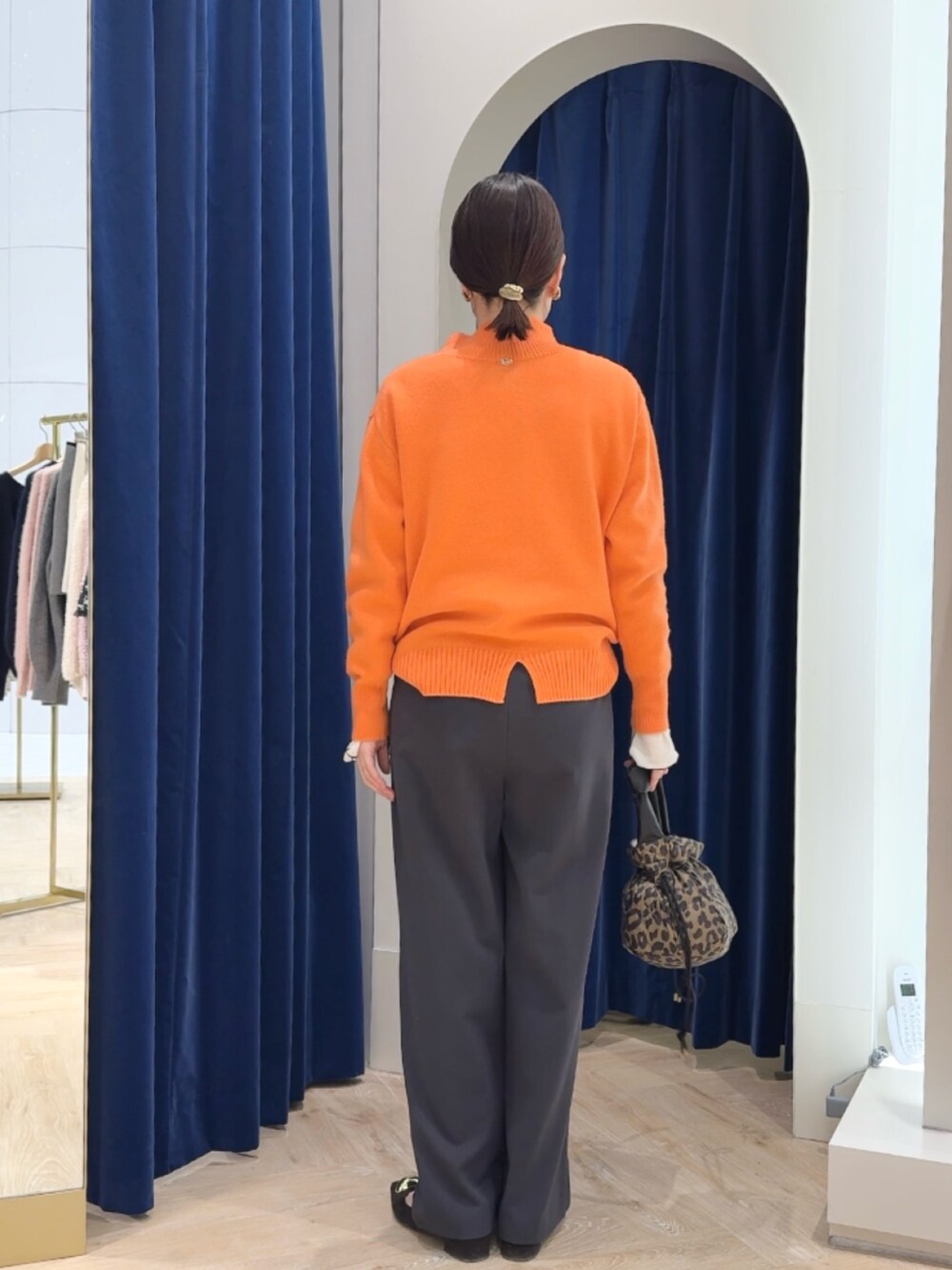 オレンジ系のニット/セーター、グレー系のその他パンツ、ホワイト系のTシャツ/カットソーを着用したレディースの冬コーディネートの4枚目の写真