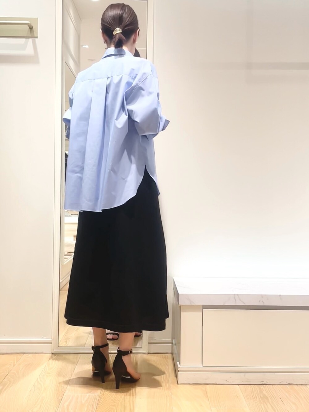 ブルー系のシャツ/ブラウス、ブラック系のワンピース、ゴールド系のイヤリングを着用したレディースの春コーディネートの4枚目の写真