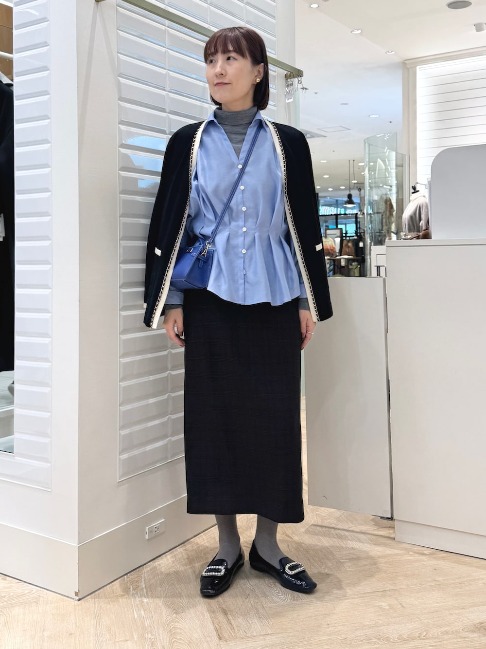 グレー系のニット/セーター、ベージュ系のスカート、ブルー系のショルダーバッグを着用したレディースの秋コーディネートの5枚目の写真