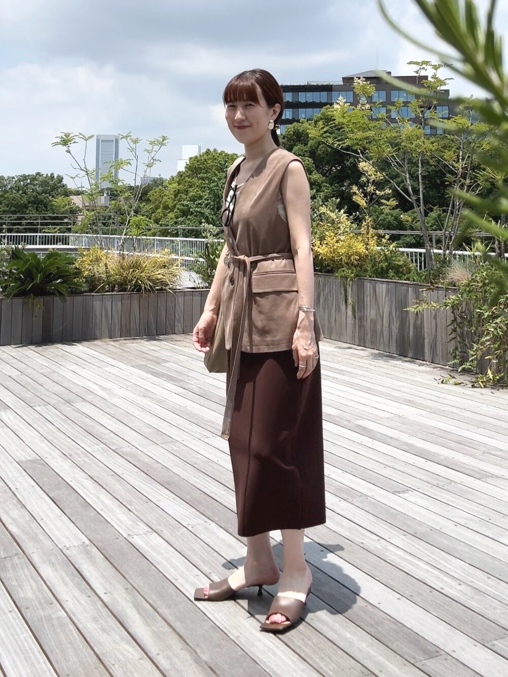 ゴールド系のタンクトップ、ベージュ系のベスト、ベージュ系のショルダーバッグを着用したレディースの秋コーディネートの4枚目の写真