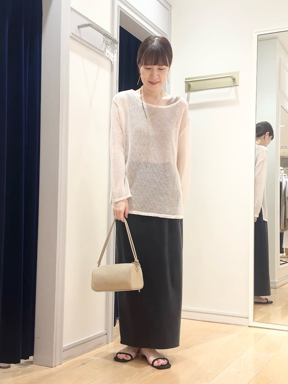ブラック系のスカート、ベージュ系のショルダーバッグ、ホワイト系のニット/セーターを着用したレディースの夏コーディネートの7枚目の写真
