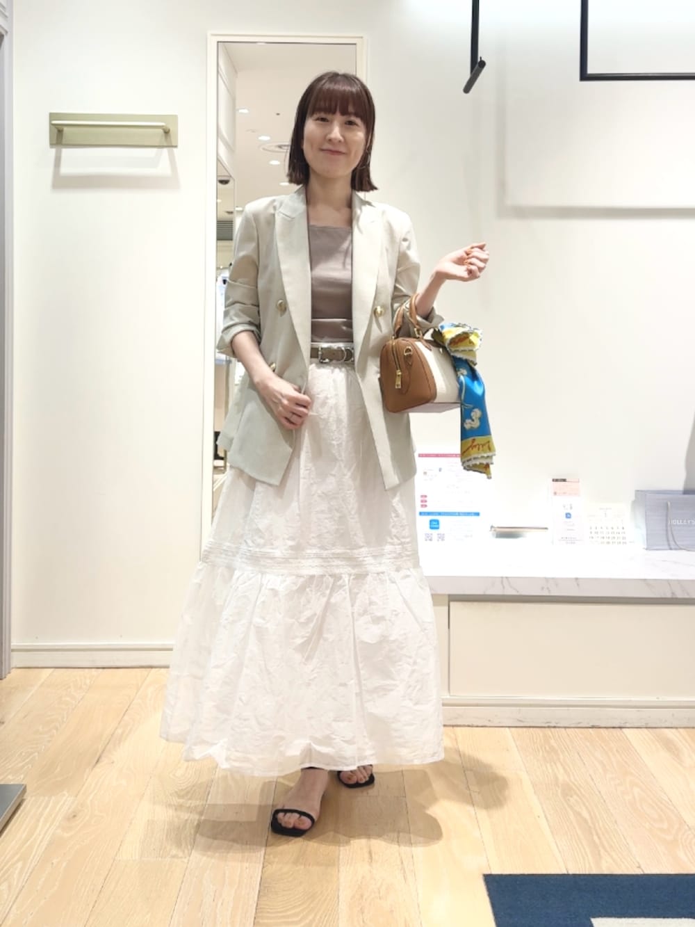 ベージュ系のテーラードジャケット、ベージュ系のタンクトップ、ブラウン系のボストンバッグを着用したレディースの春コーディネートの7枚目の写真