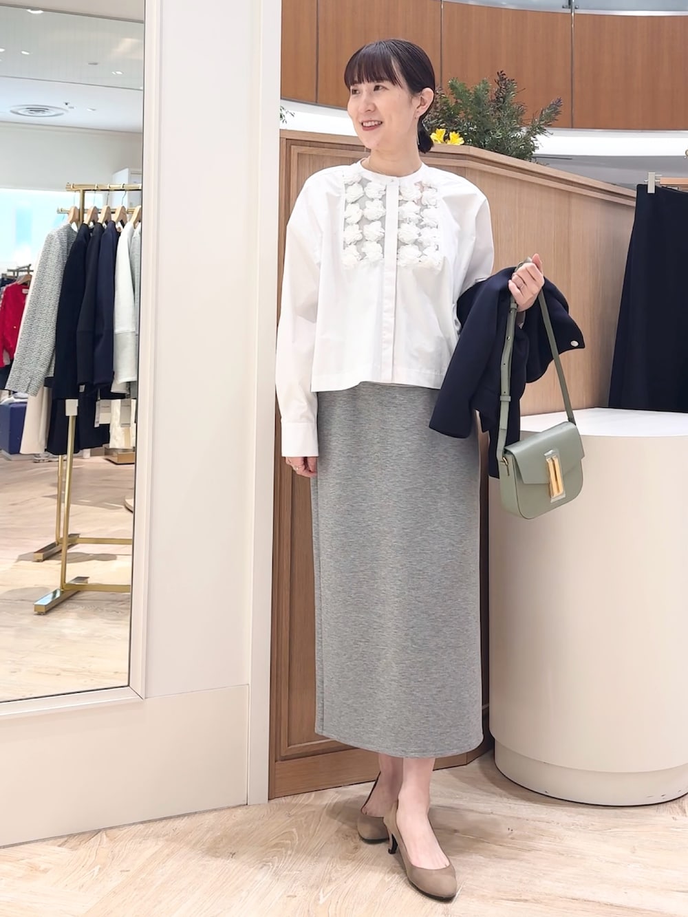 グレー系のスカート、ブルー系のブルゾン、ホワイト系のシャツ/ブラウスを着用したレディースの冬コーディネートの2枚目の写真