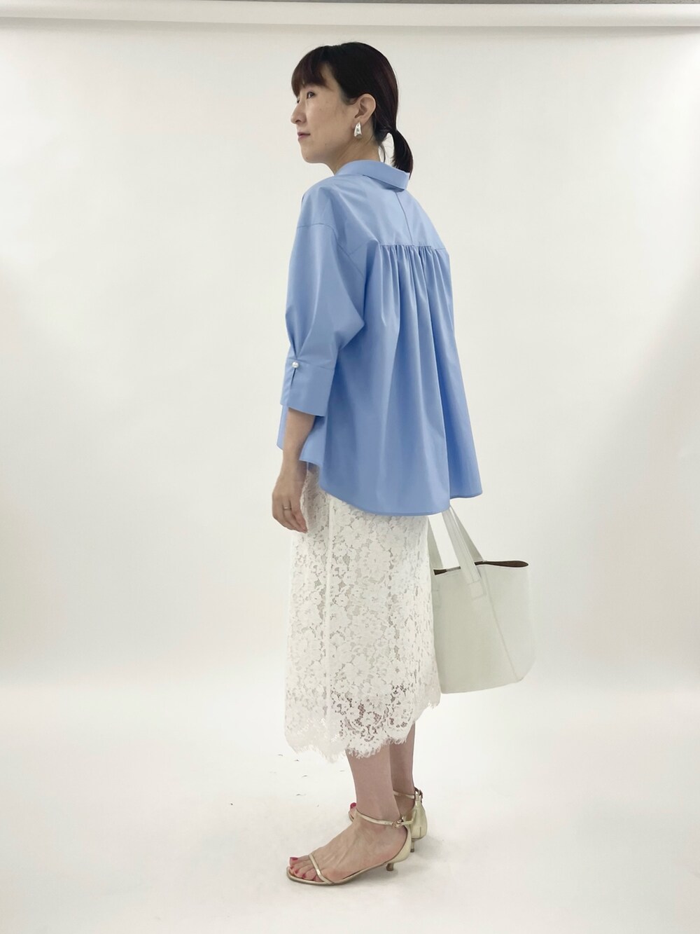 ゴールド系のサンダル、ホワイト系のスカート、ホワイト系のトートバッグを着用したレディースの春コーディネートの3枚目の写真