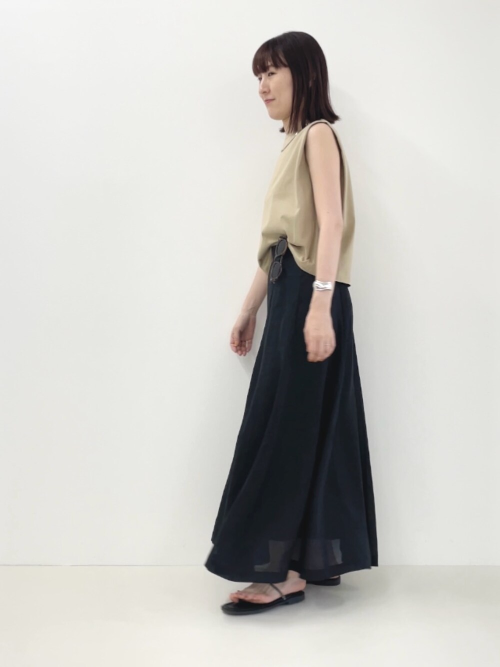 ブラック系のサンダル、ベージュ系のTシャツ/カットソー、ブラック系のスカートを着用したレディースの夏コーディネートの7枚目の写真