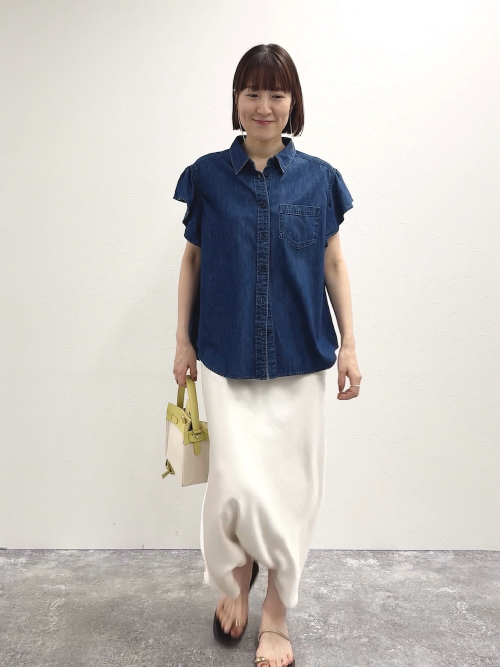 ブルー系のシャツ/ブラウス、イエロー系のショルダーバッグ、ホワイト系のスカートを着用したレディースの冬コーディネートの7枚目の写真