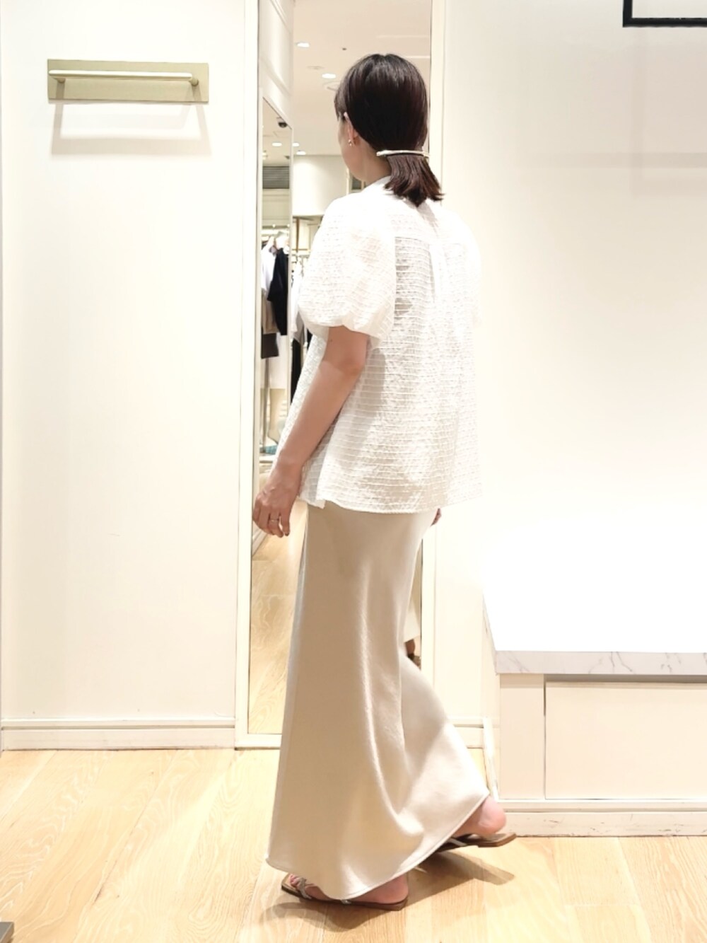 ベージュ系のスカート、ホワイト系のシャツ/ブラウス、ゴールド系のバレッタ/ヘアクリップを着用したレディースの夏コーディネートの3枚目の写真