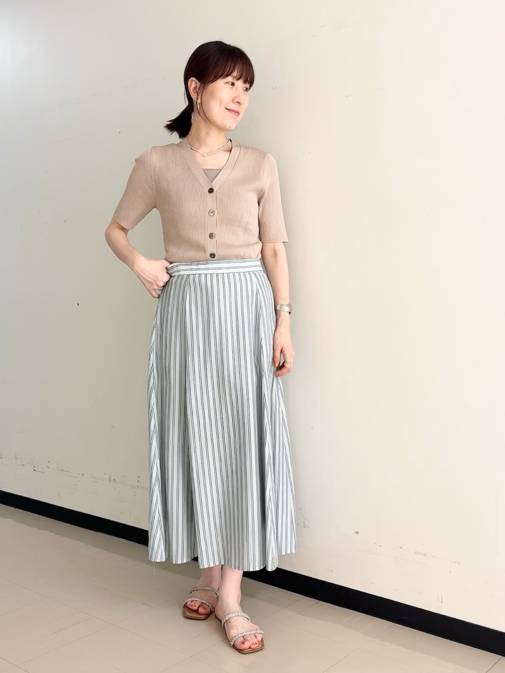 ブルー系のスカート、ベージュ系のカーディガン/ボレロ、ベージュ系のタンクトップを着用したレディースの夏コーディネートの6枚目の写真