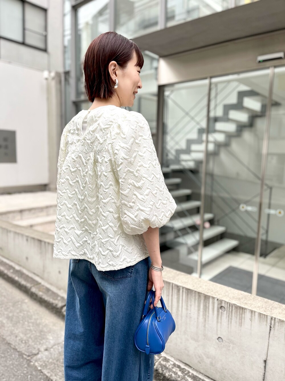ブルー系のボストンバッグ、ブルー系のデニムパンツ、ホワイト系のシャツ/ブラウスを着用したレディースの冬コーディネートの3枚目の写真
