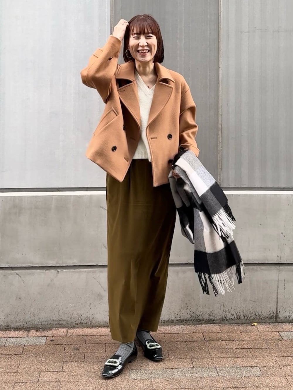 グリーン系のスカート、ホワイト系のニット/セーター、イエロー系のピーコートを着用したレディースの秋コーディネートの2枚目の写真