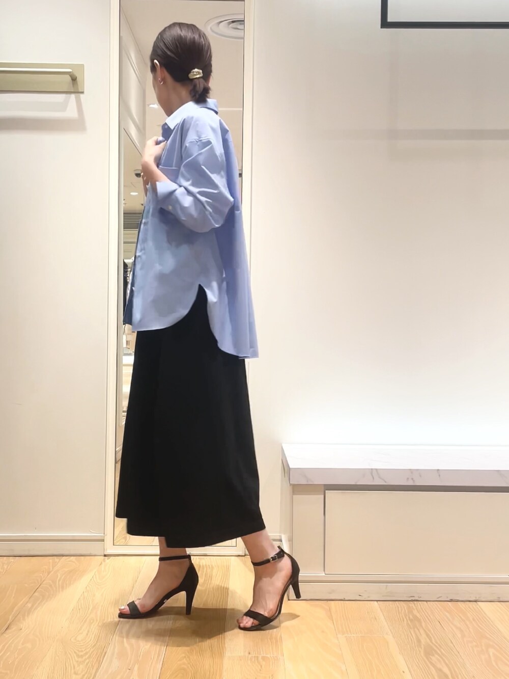 ブルー系のシャツ/ブラウス、ブラック系のワンピース、ゴールド系のイヤリングを着用したレディースの春コーディネートの3枚目の写真