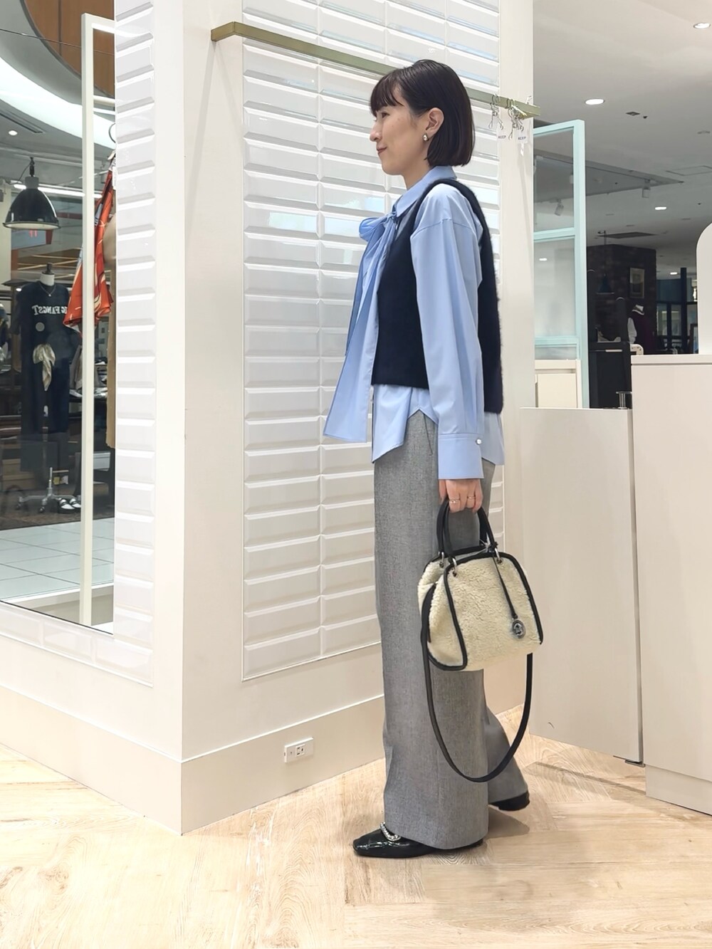 ホワイト系のボストンバッグ、ブルー系のベスト、ブルー系のシャツ/ブラウスを着用したレディースの秋コーディネートの4枚目の写真