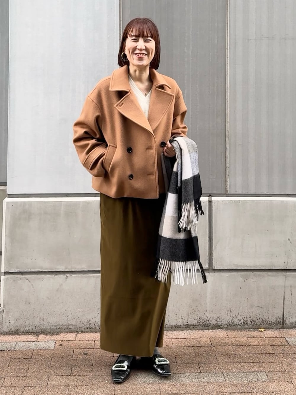 グリーン系のスカート、ホワイト系のニット/セーター、イエロー系のピーコートを着用したレディースの秋コーディネートの6枚目の写真